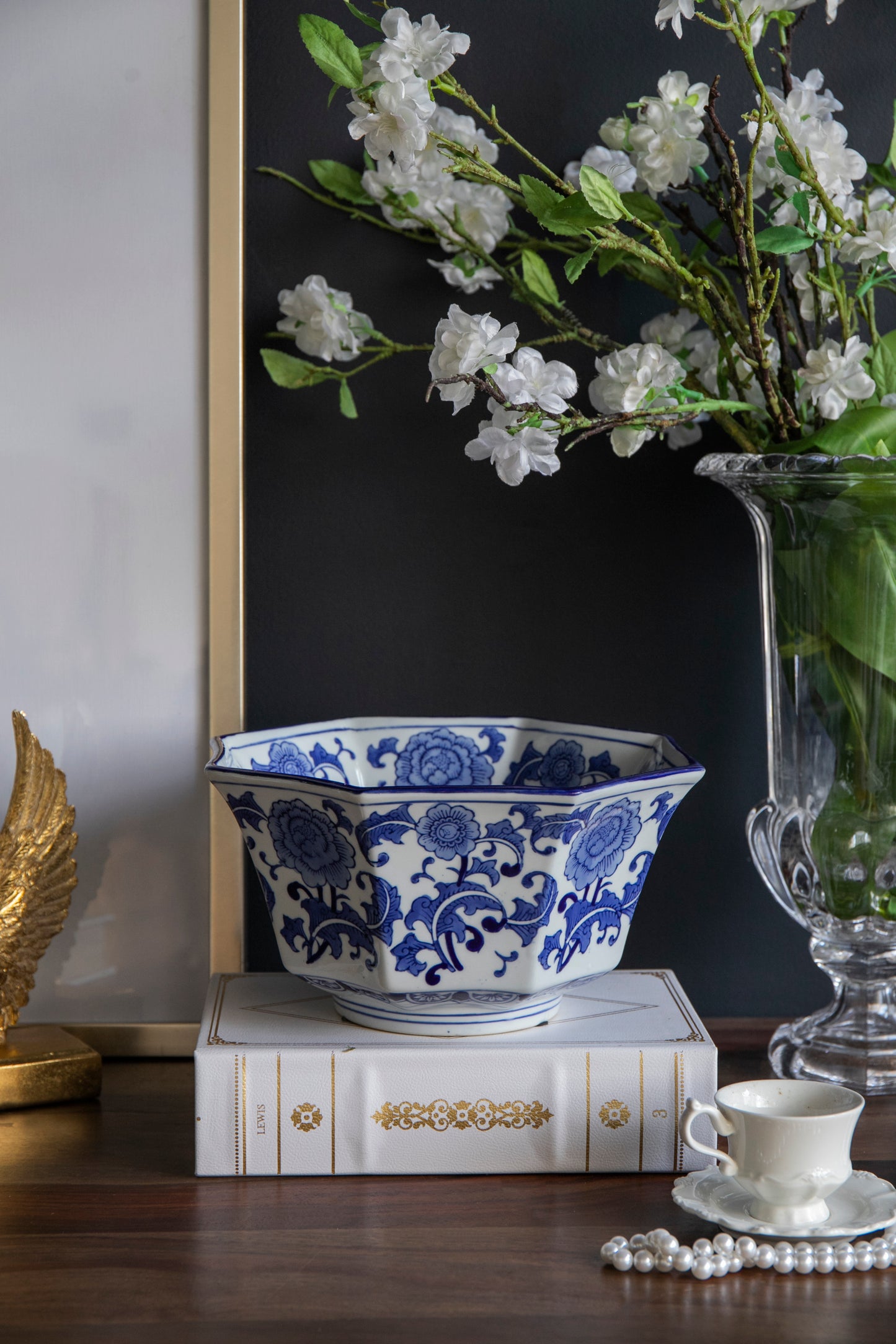 Blue and White Decorative Bowl - Porcelain, Elegant Design displayed on a wooden table with books, pearls, and floral decor.