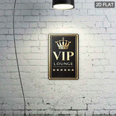 A rectangular black VIP Lounge wall sign with a gold crown and gold lettering, mounted on a white brick wall under a hanging lamp. A small &
