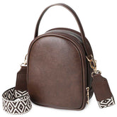 Brown leather handbag with a patterned strap on a white background