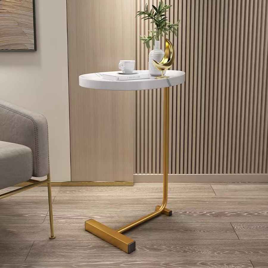 Small round marble table with gold legs in a room setting.