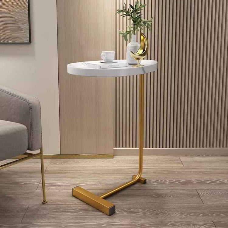 Small round marble table with gold legs in a room setting.