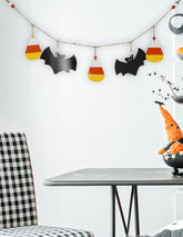 Halloween-themed decorations including bats, candy corn, and a witch on a broomstick above a table with a checkered chair.