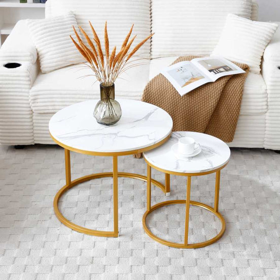 Nesting Round Coffee Table Set with white gray tops and gold metal frames placed in a modern living room with a white sofa and neutral decor.