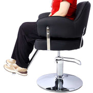 Model seated on Salon Styling Chair for Hair Stylists, showing ergonomic design and adjustable chrome base in use.