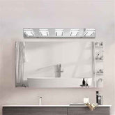 A modern rectangular bathroom mirror with an integrated LED light strip above it, mounted on a light beige wall above a white countertop and sink.
