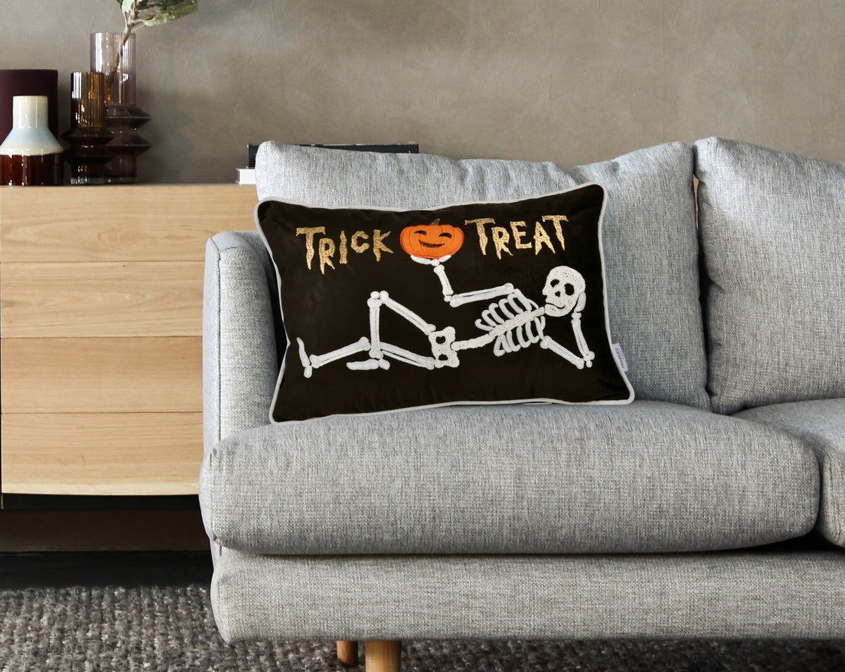 Gray sofa with a Halloween-themed pillow featuring a skeleton and &