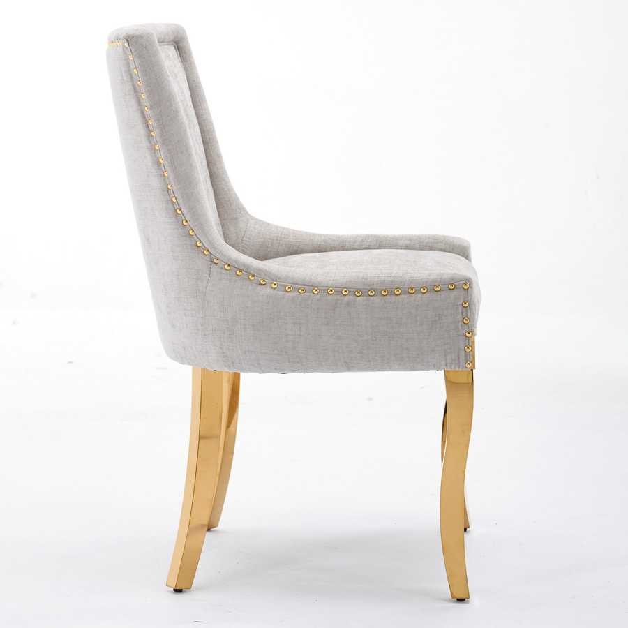 Gray upholstered chair with gold nailheads and wooden legs on a white background