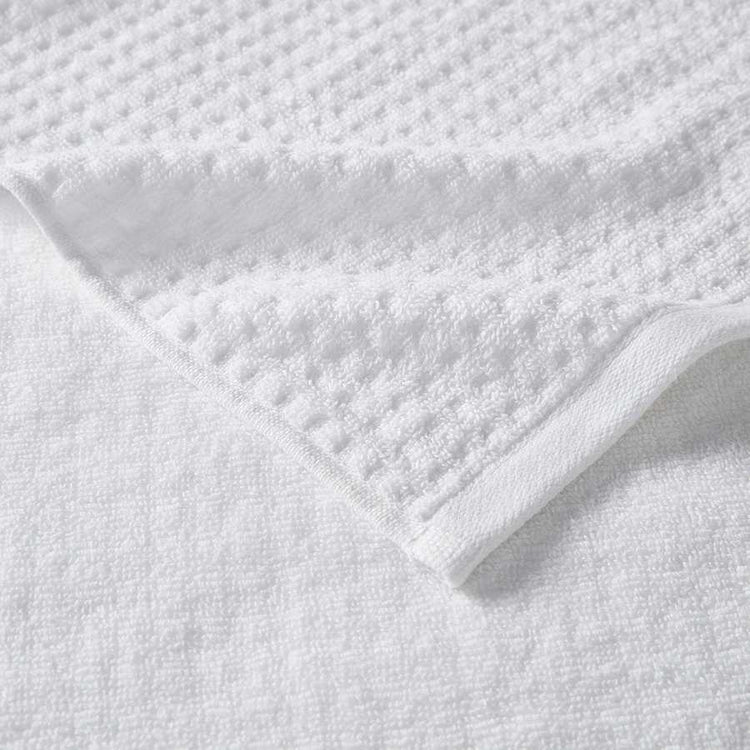 Detailed view of waffle jacquard texture on white cotton bath towel, part of the 6 piece quick drying towel set with antimicrobial treatment.