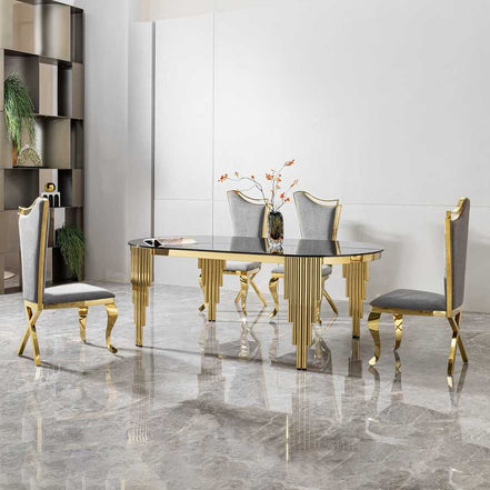 Oval dining table with black glass top and gold base shown with four gray and gold chairs in a luxury dining room setup.