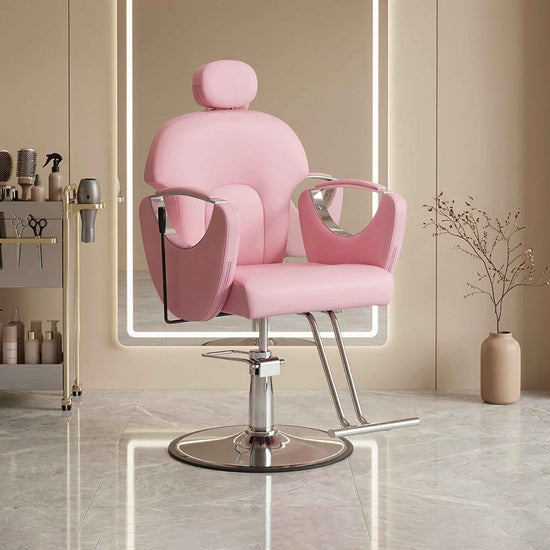 A pink salon barber chair with a chrome hydraulic base, shown in a modern, softly lit beauty salon interior.