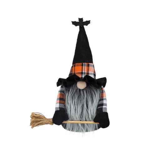 A Halloween witch gnome decoration with a tall black pointed hat topped by a small bat figure, an orange, black, and white plaid band, a gray faux-fur beard, black hands, and a broom on a wooden handle.