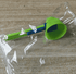 Green and blue measuring scoop on a wooden surface with clear plastic wrap.