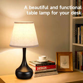 Table lamp on a desk with books and a cup, text &