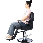 Barber Chair - Heavy Duty Hydraulic with PU leather and adjustable backrest shown upright with person seated. Ideal for salon professionals.
