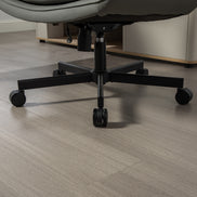 Close-up of a chair's black metal base on a wooden floor.