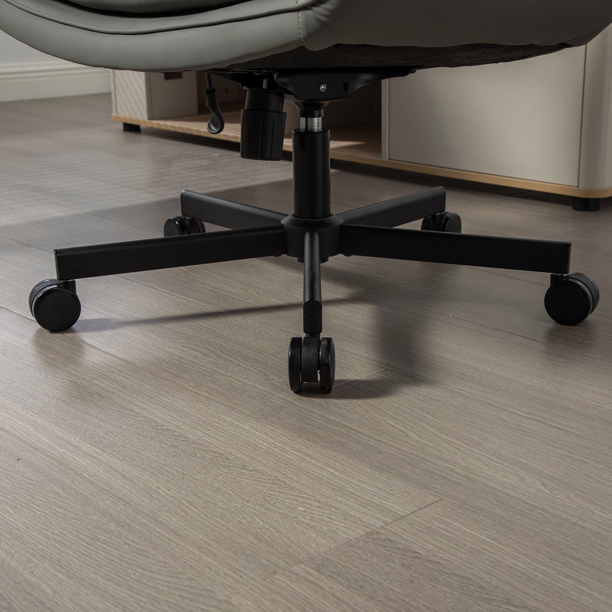 Close-up of a chair's black metal base on a wooden floor.