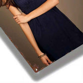 A close-up lifestyle shot of a woman wearing a dark navy blue sleeveless dress, shown from the chest down, with her arms crossed. She is wearing a gold chain bracelet on her wrist.
