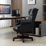 Black office chair in front of a desk with a computer setup in an office setting.