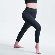 Person wearing black leggings on a light gray background