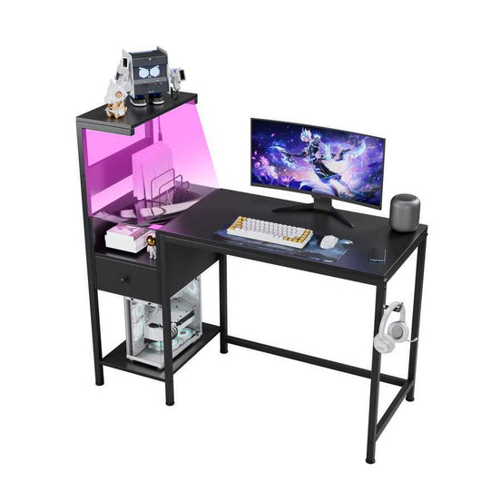 Black computer desk with USB charging station and LED lighting, featuring a monitor, keyboard, and reversible storage shelves.