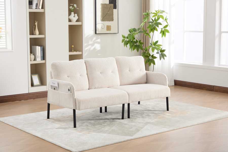 Beige sofa in a living room with a rug and bookshelf.