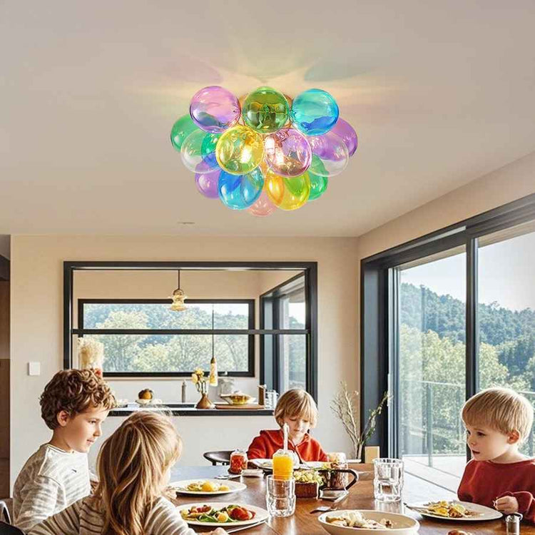 Children sitting at a dining table with a colorful balloon-like ceiling light fixture.