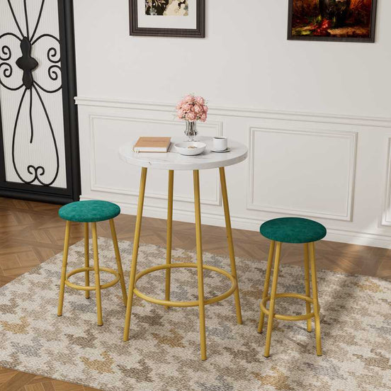3-Piece Bar Table Set with Stools featuring a white round tabletop and gold legs, paired with green cushioned stools in a modern living space.