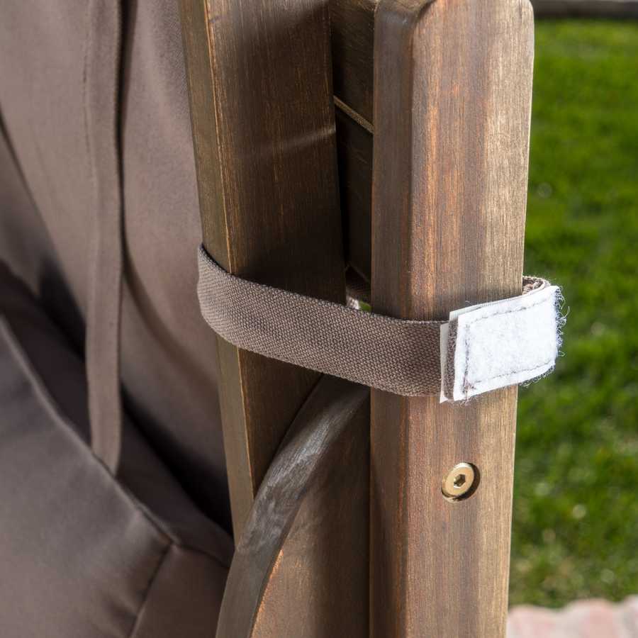 Close-up of a wooden chair with a strap and button, blurred green grass in the background