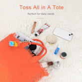 Orange tote bag with daily necessities on a white textured surface