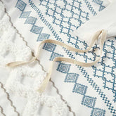 Textile with blue geometric pattern and natural fiber strap on a textured white surface