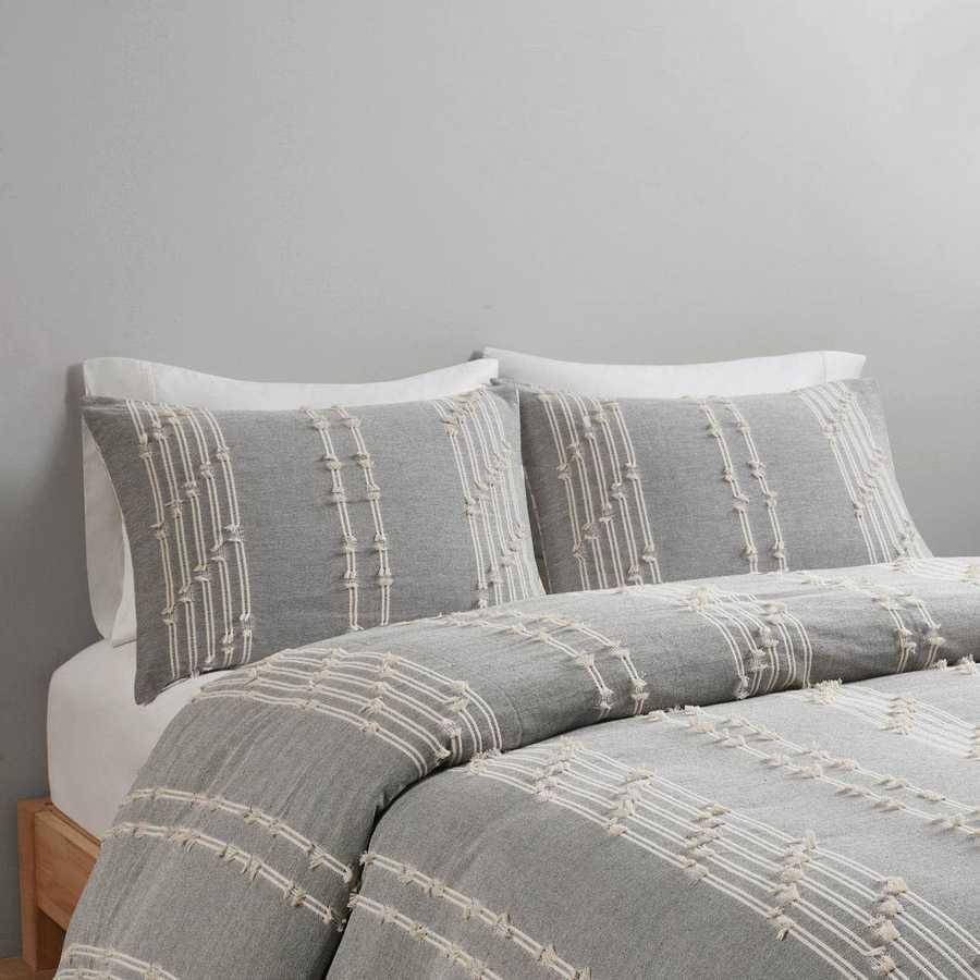 Gray and white patterned bedding set on a bed against a gray wall.