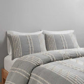 Gray and white patterned bedding set on a bed against a gray wall.
