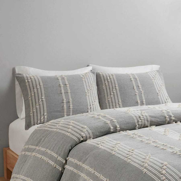 Gray and white patterned bedding set on a bed against a gray wall.
