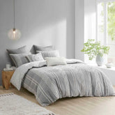 Gray and white patterned comforter set on a bed in a modern bedroom with natural light.