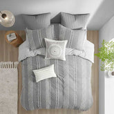 Gray and white patterned bedding set on a bed with decorative pillows.