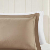 Close-up of beige pillow with white pillowcase on a neutral background