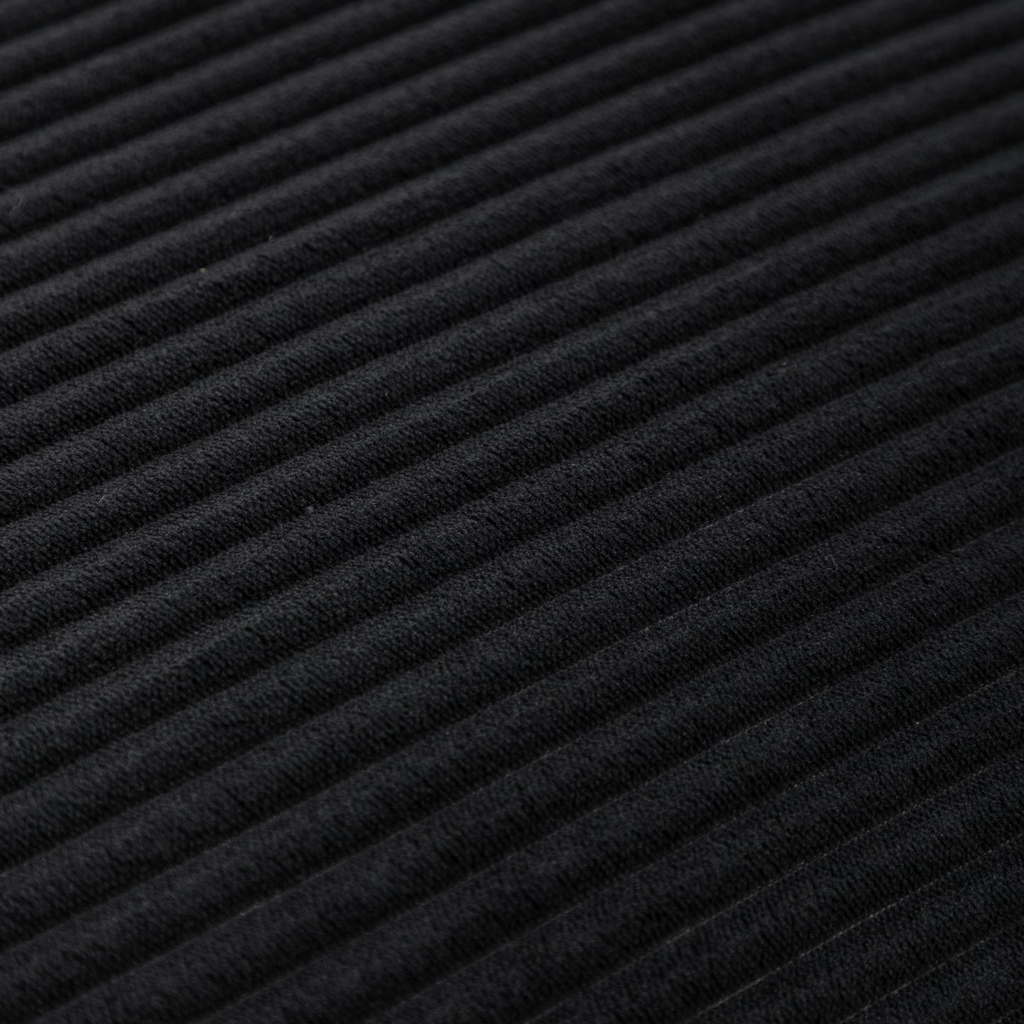 Close-up texture of black corduroy fabric on bean bag chair, highlighting soft ribbed material for stylish comfort.