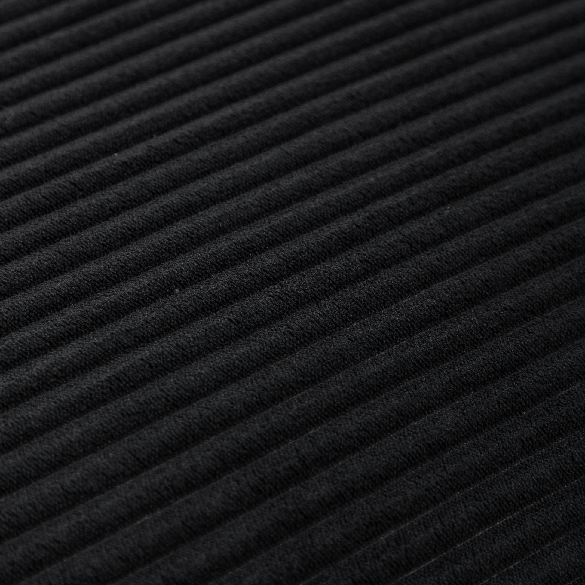 Close-up texture of black corduroy fabric on bean bag chair, highlighting soft ribbed material for stylish comfort.