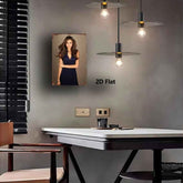 A framed portrait print of a woman in a navy dress displayed on a gray wall above a white table in a modern room. The print has a rustic distressed border and the text &