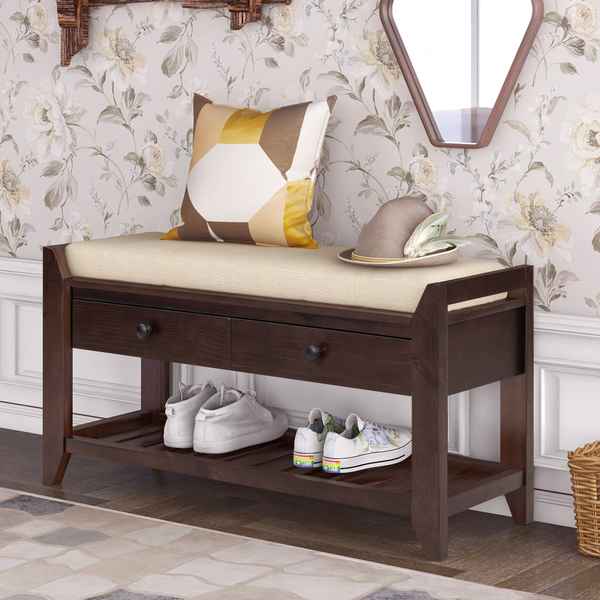 Wooden bench with cushion, shoes on the shelf, and decorative pillows against floral wallpaper.