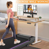 A woman exercising on a compact treadmill with a monitor, in a modern home office setup, promoting exercise while working