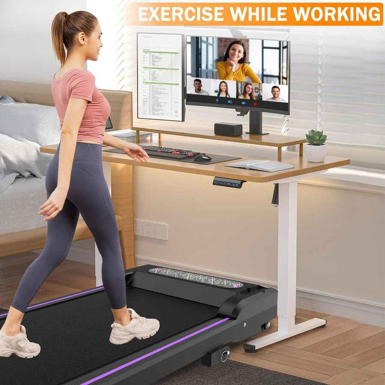 A woman exercising on a compact treadmill with a monitor, in a modern home office setup, promoting exercise while working