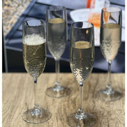 Set of 4 unbreakable plastic champagne flutes with sparkling wine, perfect for toasting at outdoor events or casual celebrations.