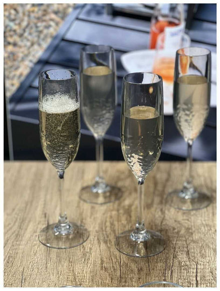 Set of 4 unbreakable plastic champagne flutes with sparkling wine, perfect for toasting at outdoor events or casual celebrations.