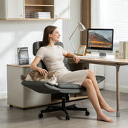 Woman sitting on a modern office chair with a cat, working at a desk in a bright room.