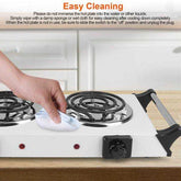 Person cleaning electric stove burners with damp cloth