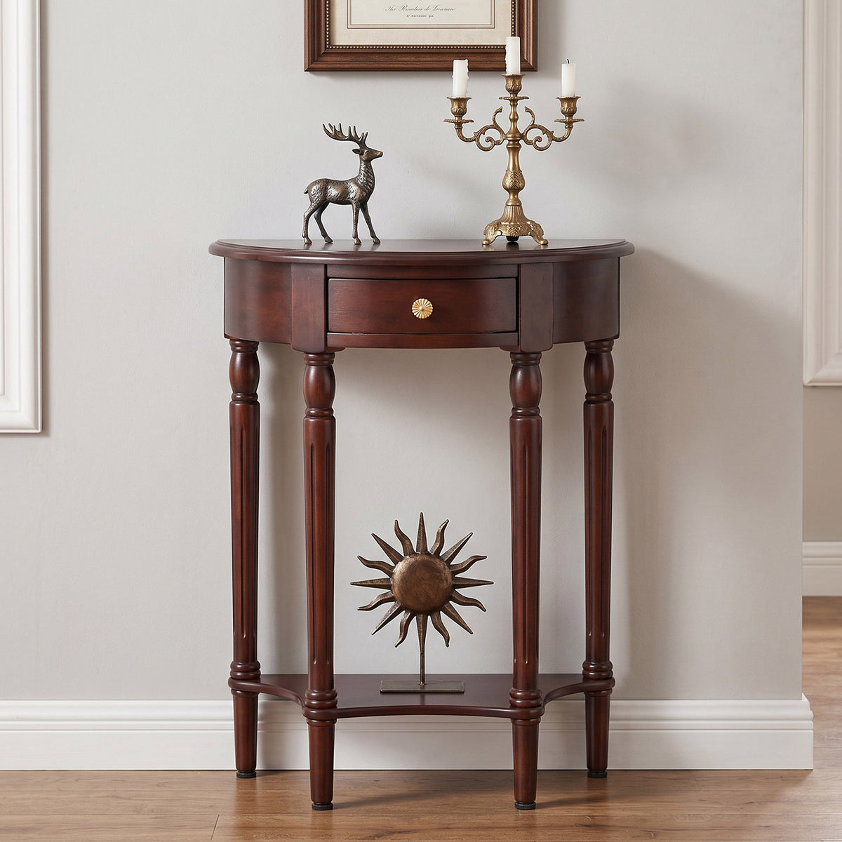 A dark brown wooden console table with a single drawer, turned legs, and a lower shelf featuring a sunburst metal ornament. The table is styled with a bronze deer figurine and a brass candelabra against a neutral wall.