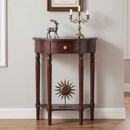 A dark brown wooden console table with a single drawer, turned legs, and a lower shelf featuring a sunburst metal ornament. The table is styled with a bronze deer figurine and a brass candelabra against a neutral wall.