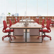 Modern office setup with red chairs and wooden tables in a bright room.