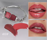 A silver-tone chain bracelet with a lipstick-shaped charm showing two shades of pink-red lipstick. Two inset photos show glossy lips wearing the shade, and a lipstick smear below indicates color 03